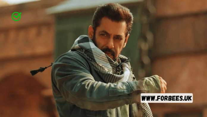 Salman Khan posing in a casual outfit, with his iconic bracelet visible, against a backdrop of Bollywood